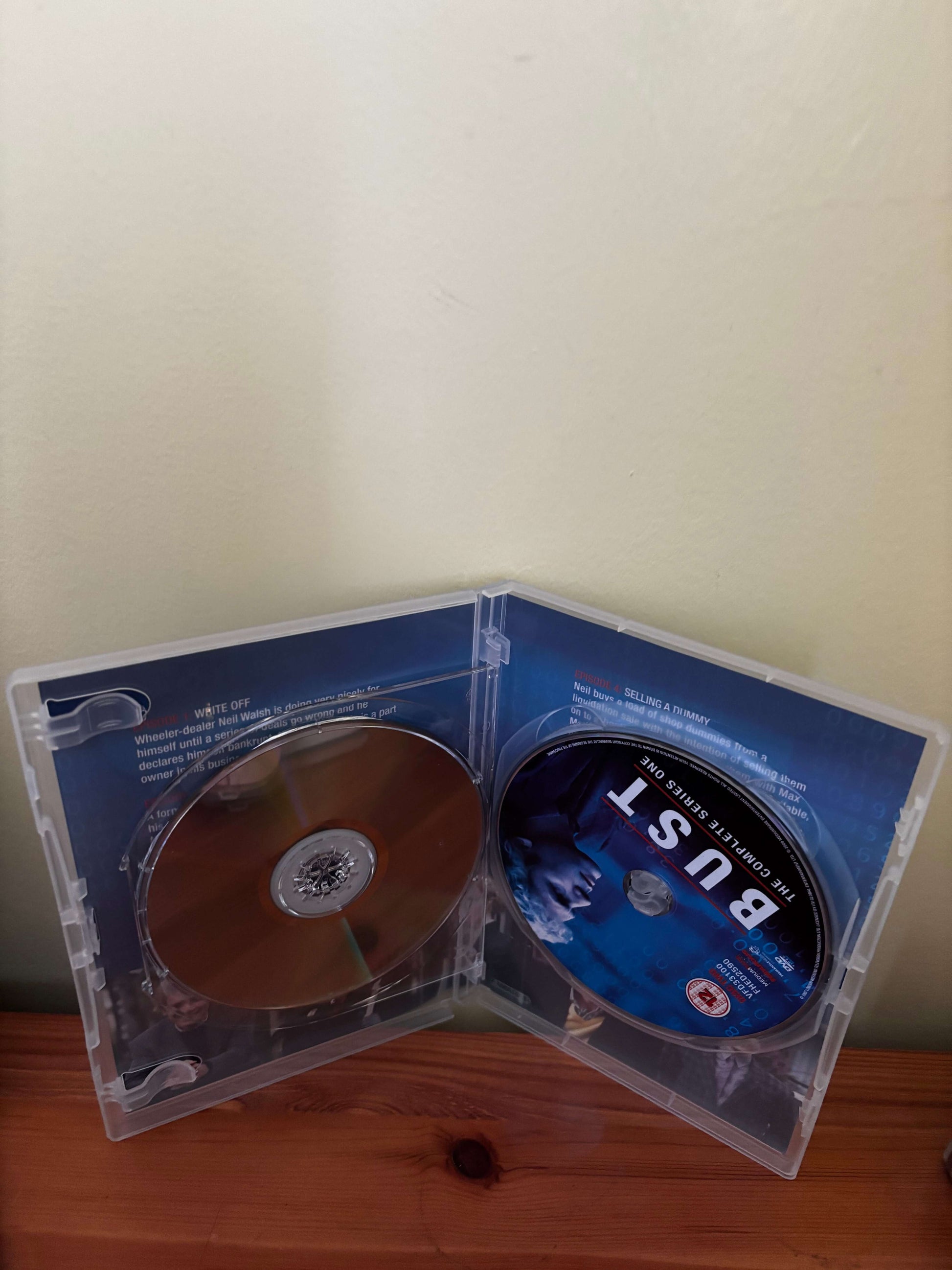 Open DVD case with a disc inside on a wooden surface