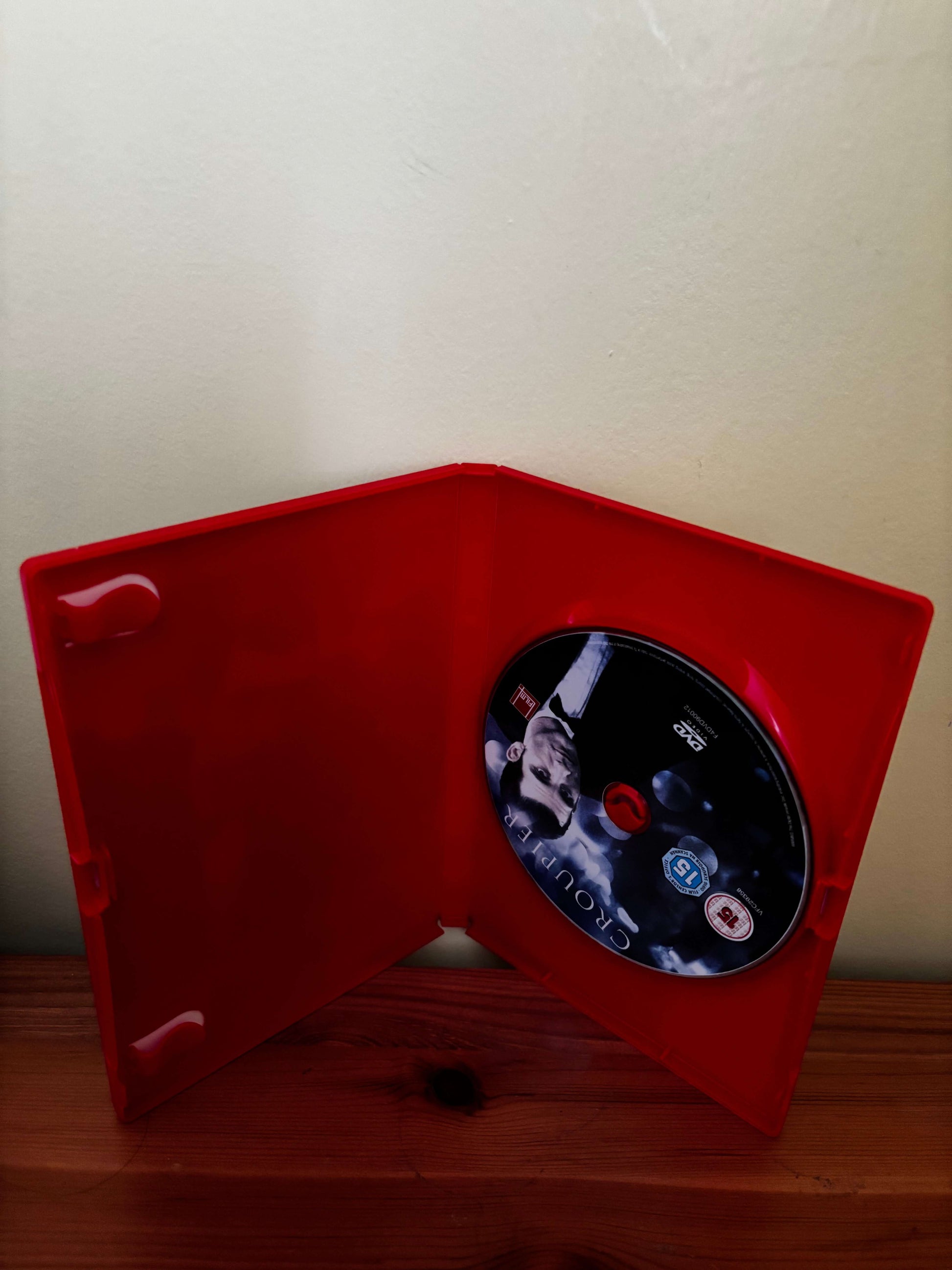 Red rectangular object with a circular component featuring cartoon characters on a white wall.