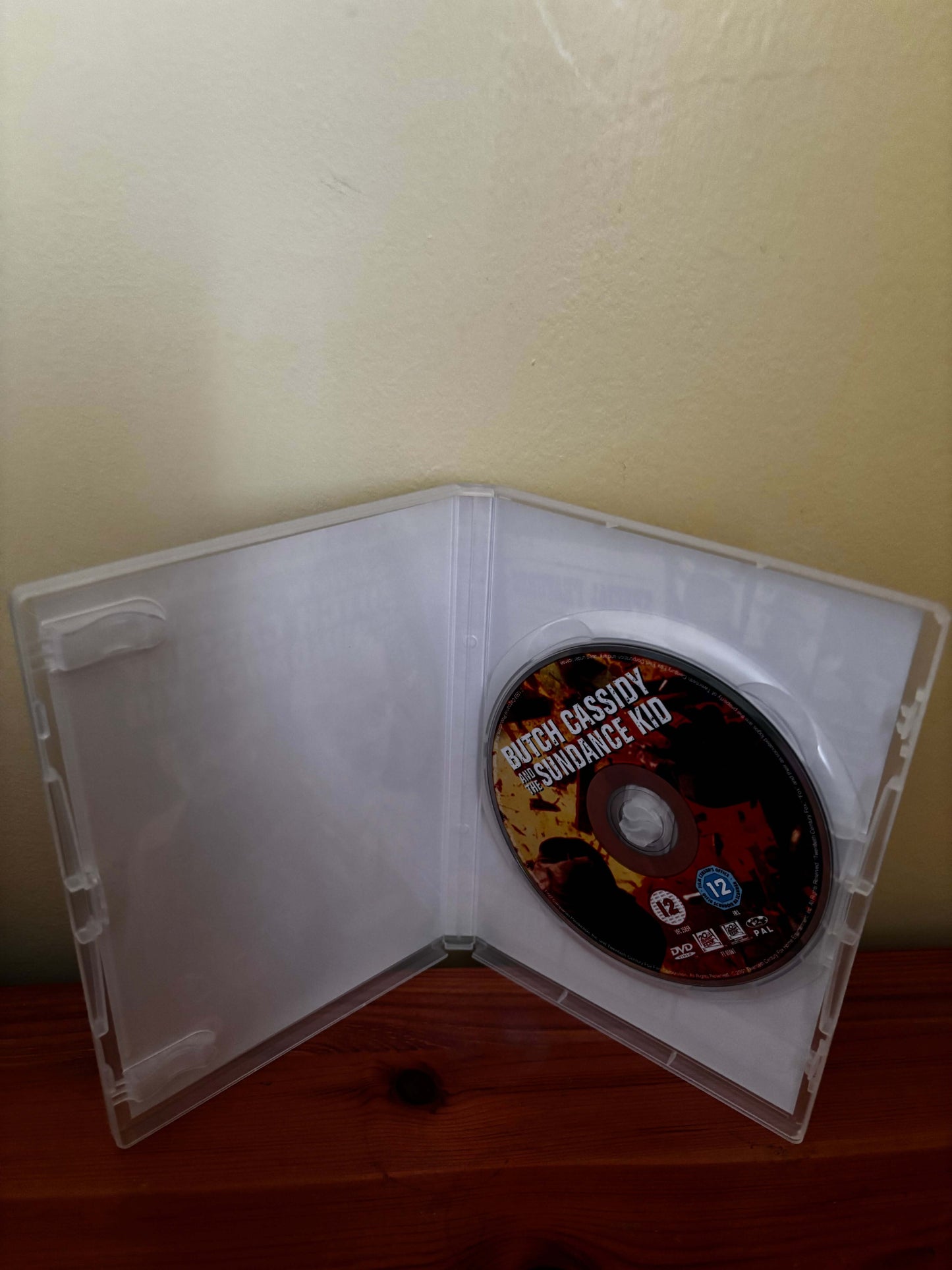 Open DVD case with a disc inside on a wooden surface