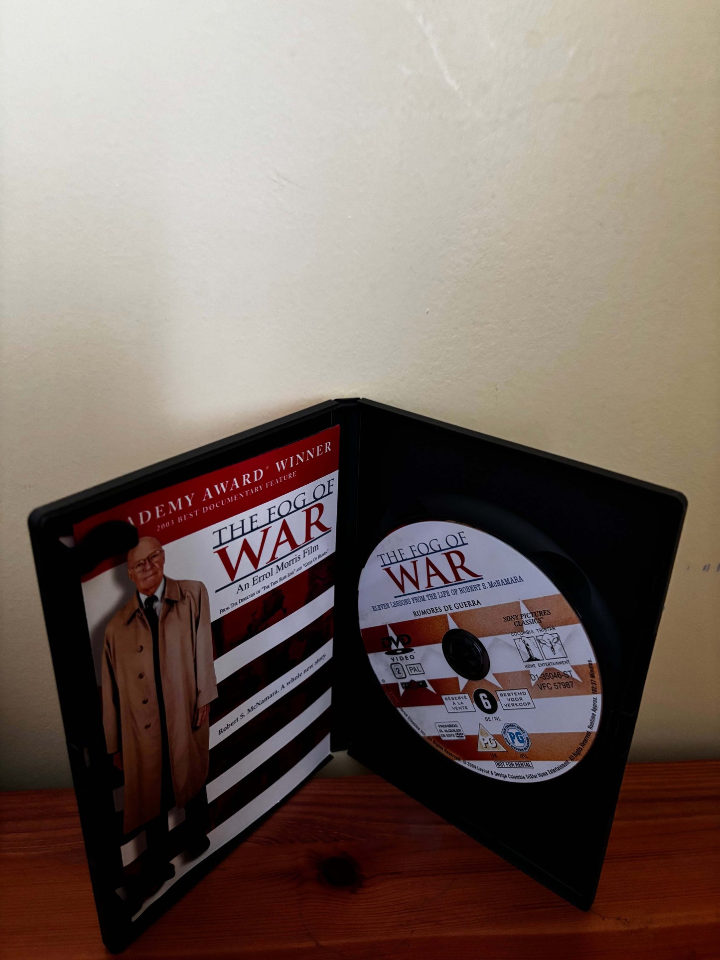 DVD case and disc titled 'The Fog of War' on a wooden surface with a beige wall background.