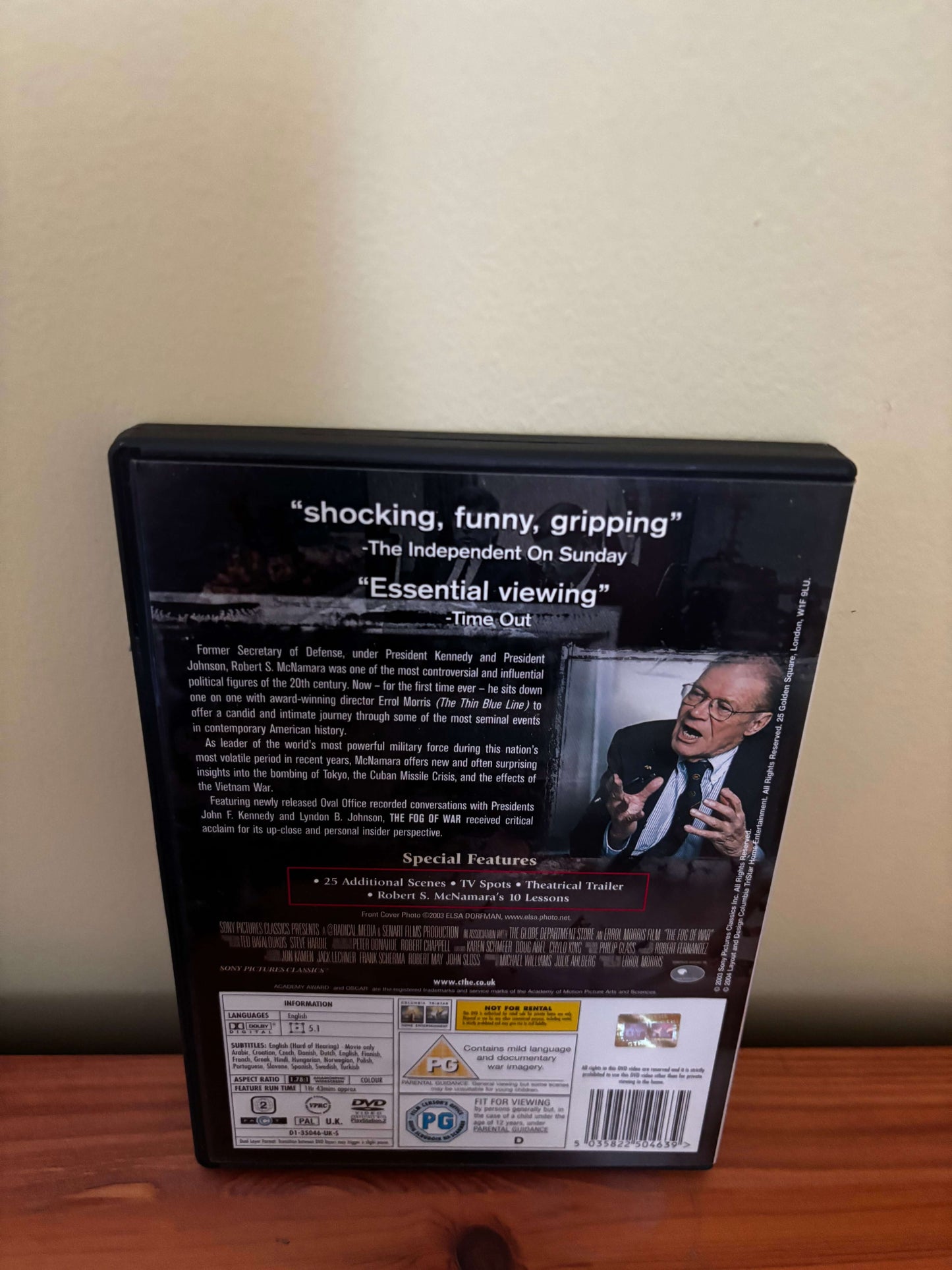 DVD case with text and a person on the back, placed on a wooden surface.