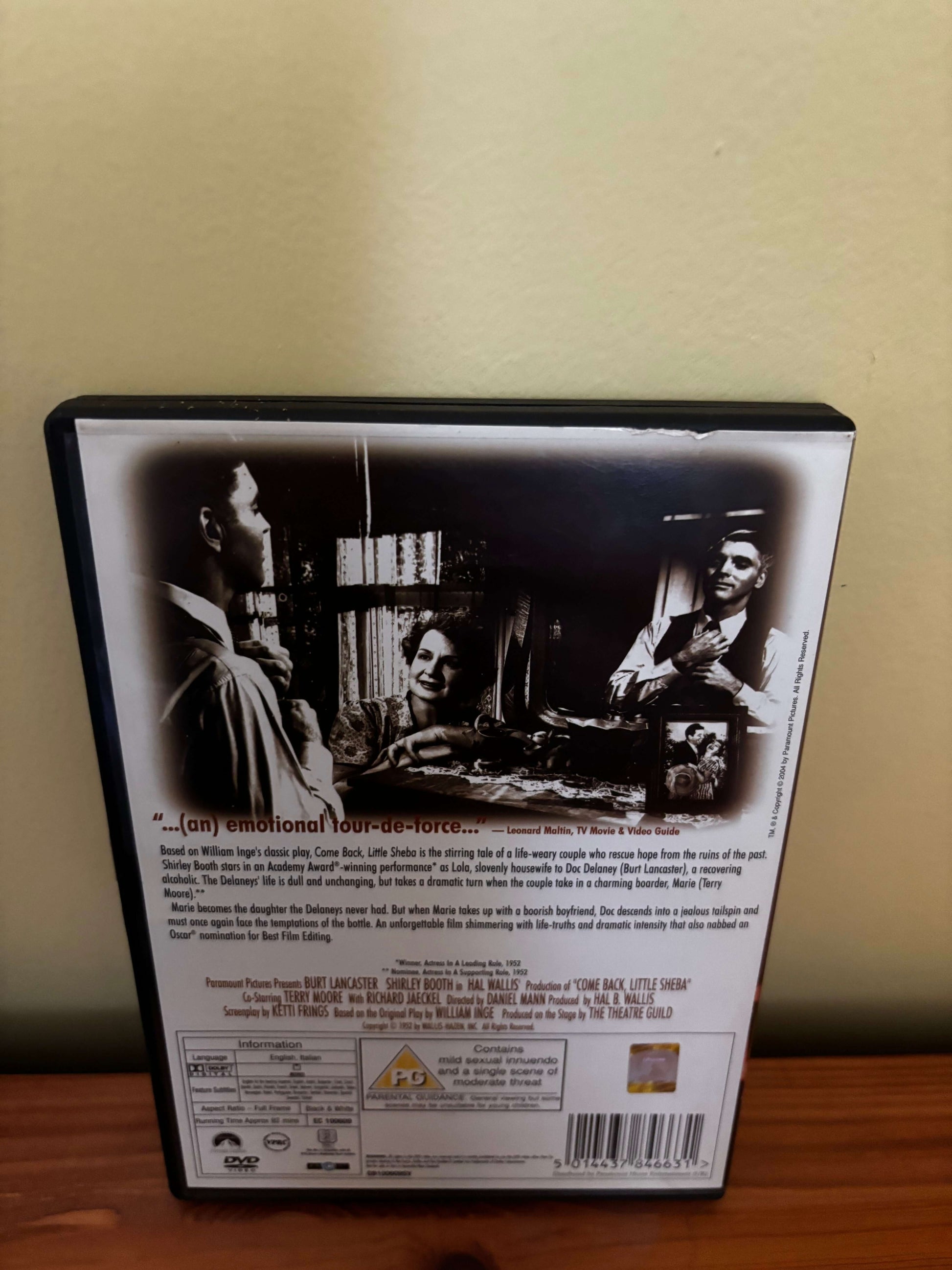 DVD case with black and white images of people and text on a wooden surface.