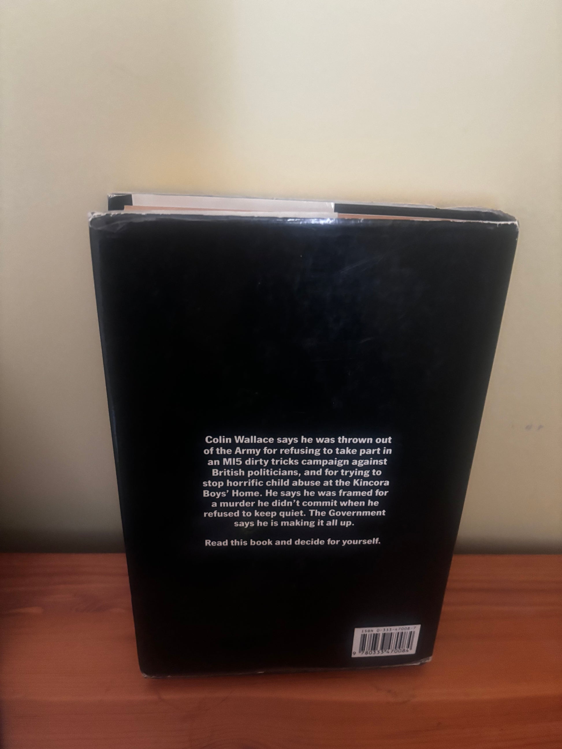 Black book with text and a barcode on a wooden surface