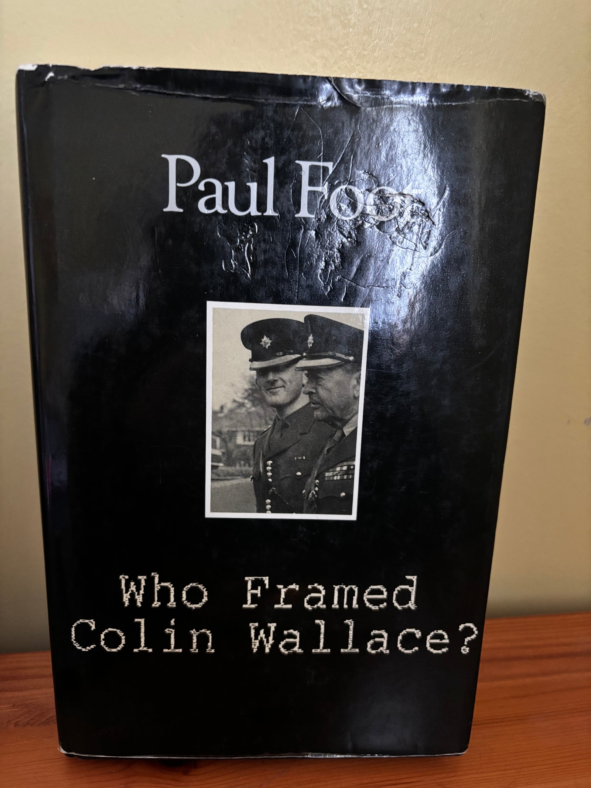 Book titled 'Who Framed Colin Wallace?' with a black cover and portrait of two men in uniform.