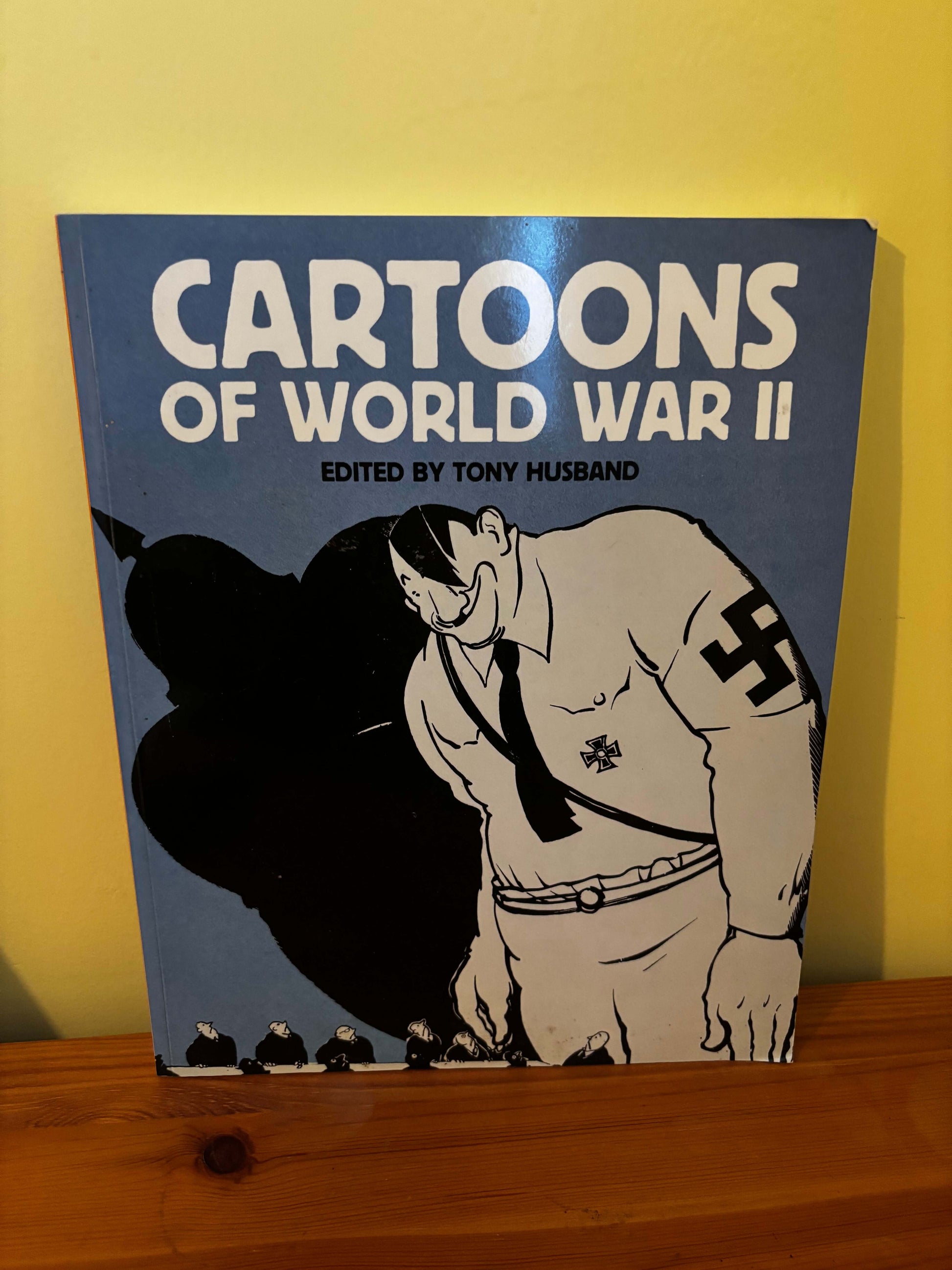 Book titled 'Cartoons of World War II' with a cover illustration on a yellow surface.