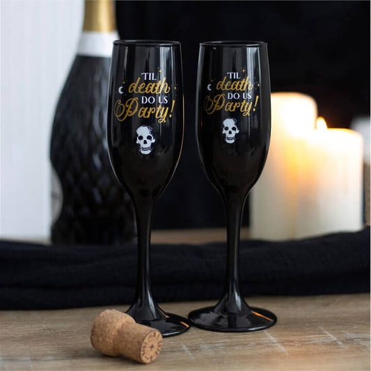 Til Death Do Us Party Champagne Flute Set Two Glasses displayed with candles and cork on a table.
