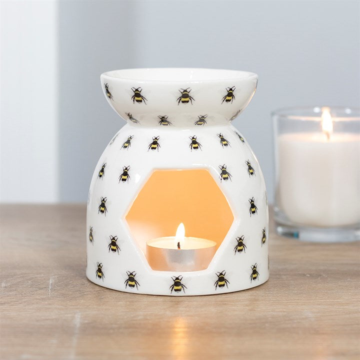 All Over Bee Print Oil Burner, white ceramic fragrance warmer with bee pattern and a warm candle glow.
