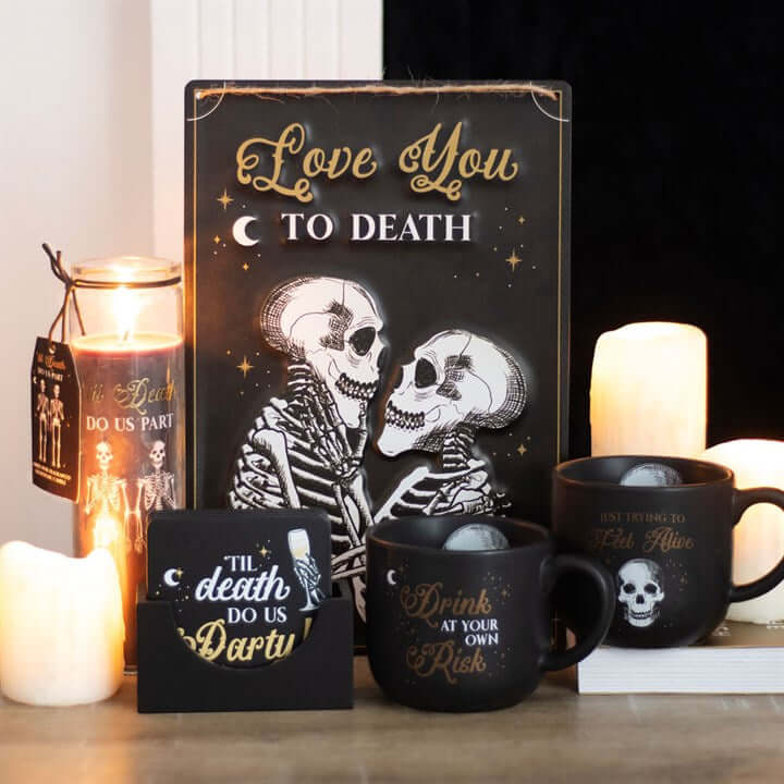 Til Death Do Us Part Amber Noir Tube Candle With Skeleton Couple Design on display with mugs and decor.