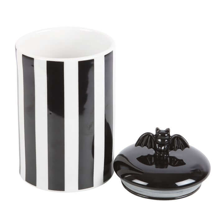 Striped ceramic storage jar with bat-detail lift-off lid; black and white vertical stripes.