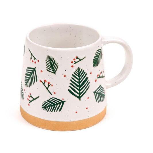 Stoneware mug with green pine sprigs and red berries on white ceramic, tan base.