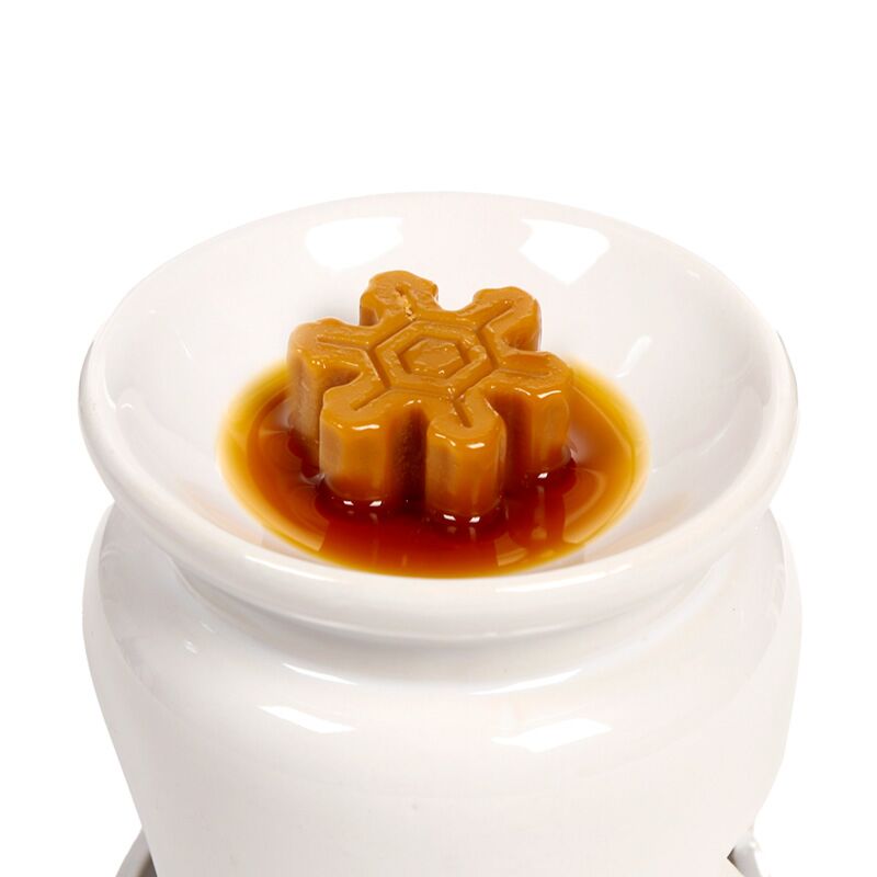 Handmade wax melt, star-shaped in amber, melting on a white ceramic burner dish—Winter Spice fragrance.