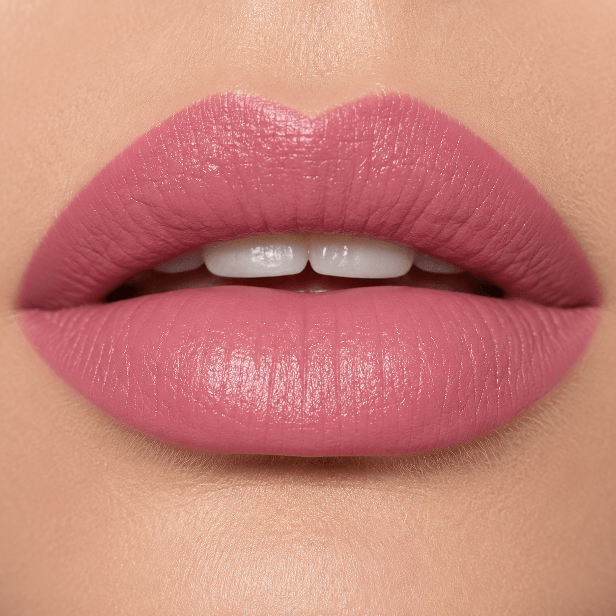 Close-up of a person's lips wearing a matte dusty rose pink lipstick, showing the texture and color of the makeup on the skin.