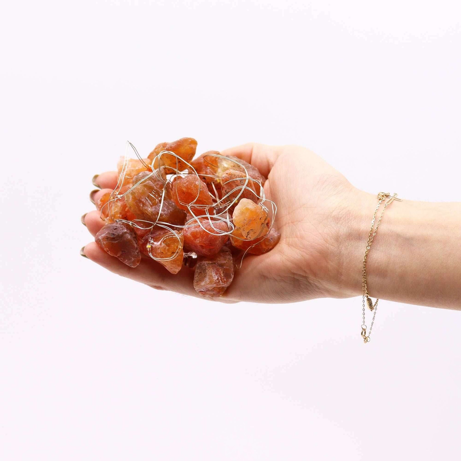 Hand holding a cluster of Orange Jade gemstones for Orange Jade Gemstone Lights Crystal LED Glow.