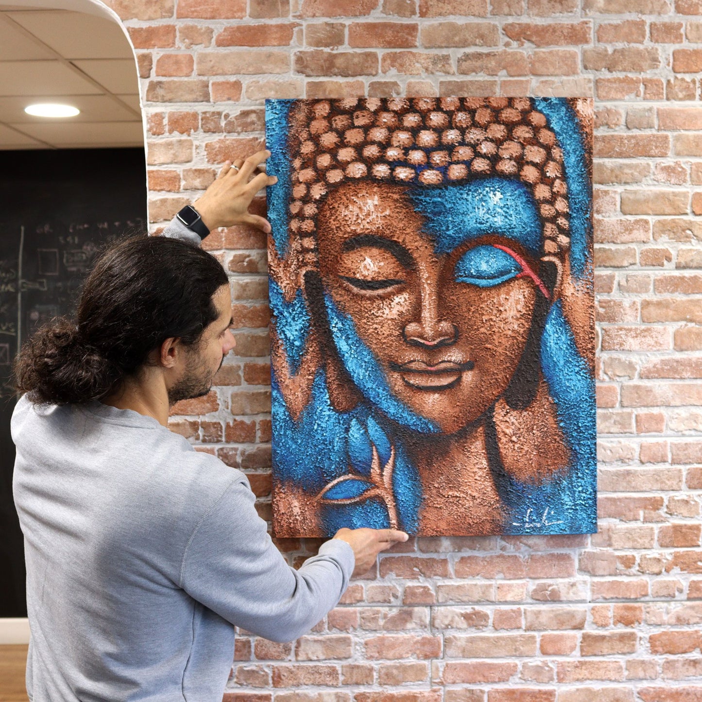 Buddha Painting - Silver serene Buddha head with blue highlights on brick wall.