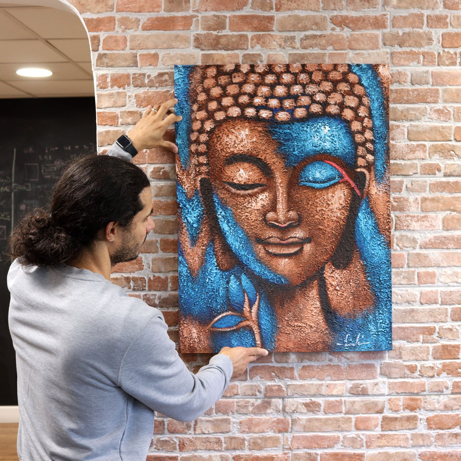 Buddha Painting - Silver serene Buddha head with blue highlights on brick wall.