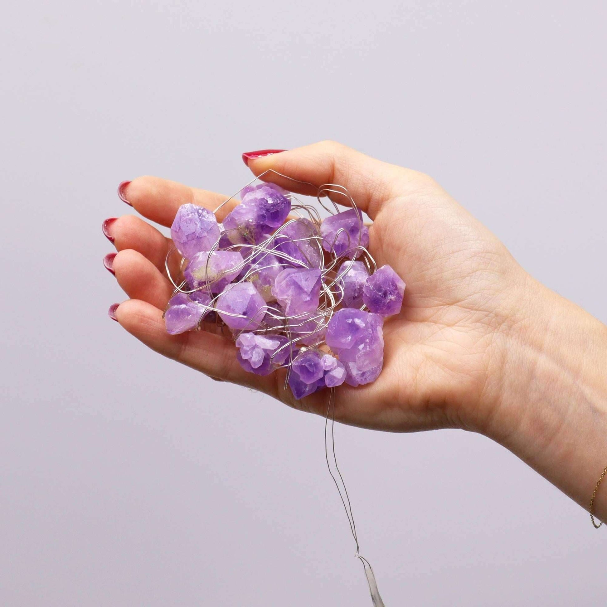 Amethyst Gemstone Enchantment Lights USB String held in hand with glowing purple crystals.
