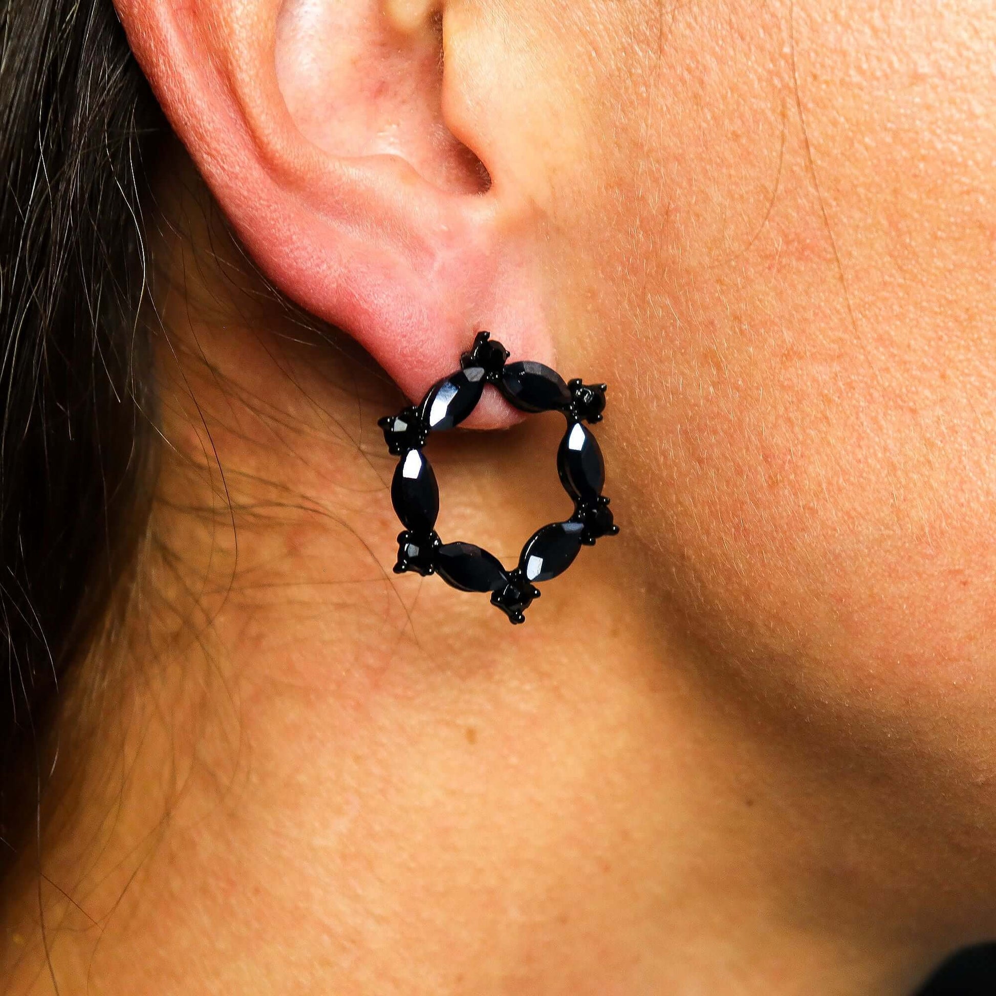Jet Black Vintage Glass Loop Earrings by Nymph Aurora worn in an ear, showcasing their elegant design and glossy finish.