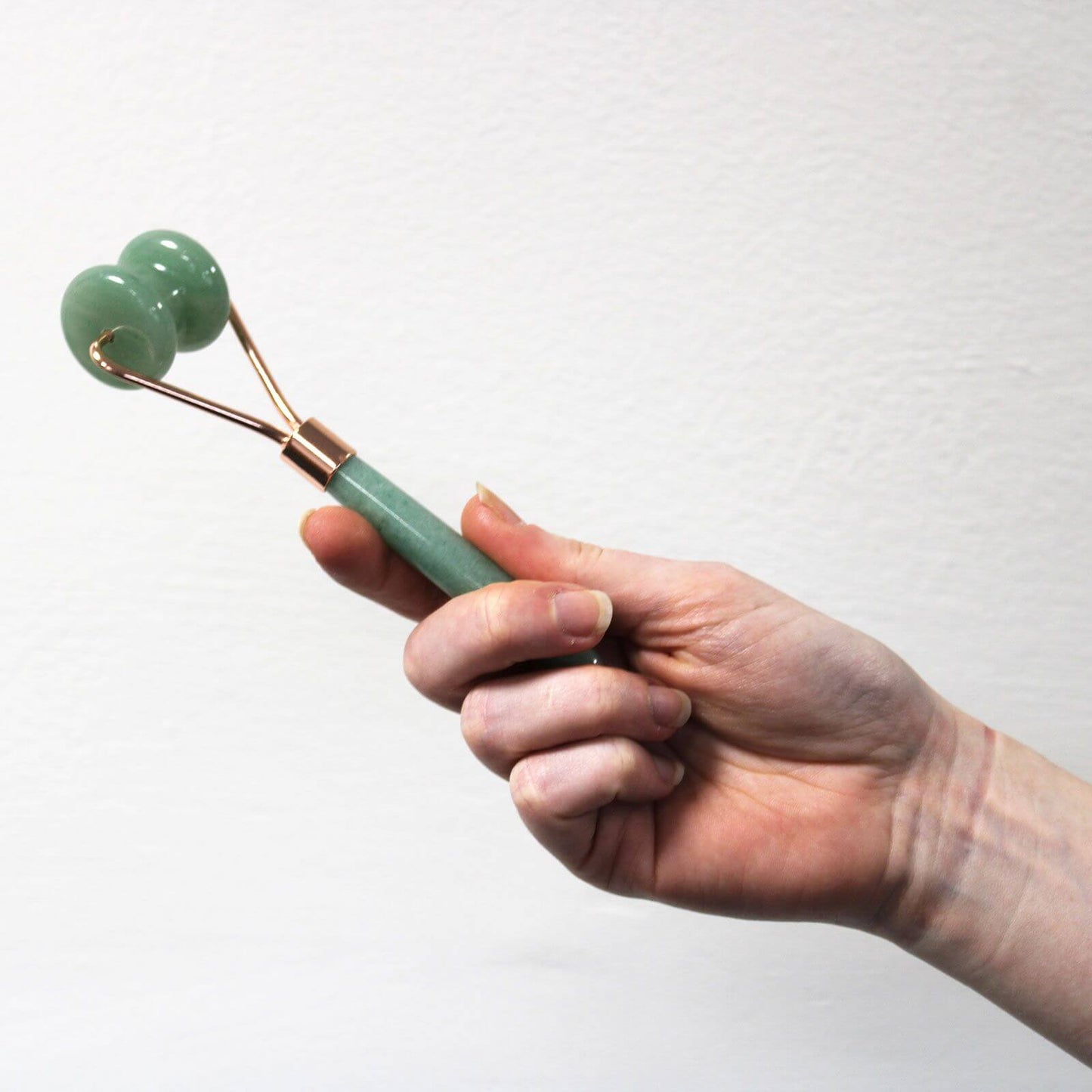 Gemstone Mini Jade Roller For Facial Massage Travel Size held in a hand, featuring a green jade design and brass accents.