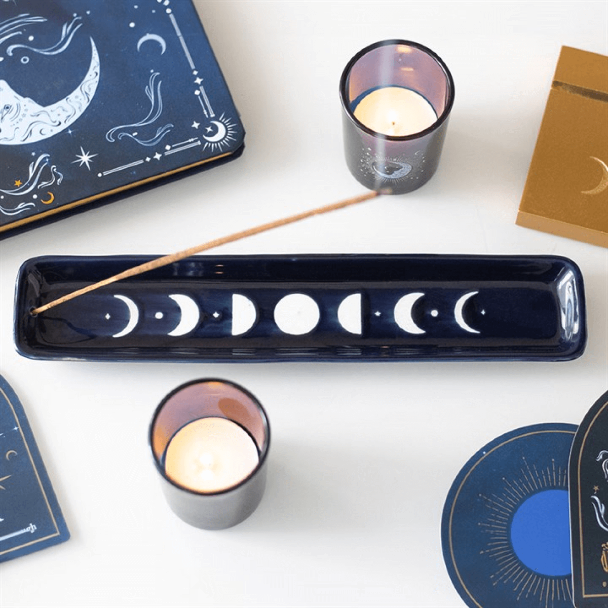 Blue Moon Phase Ceramic Incense Ash Catcher With Celestial Design displayed with candles and moon phase items.