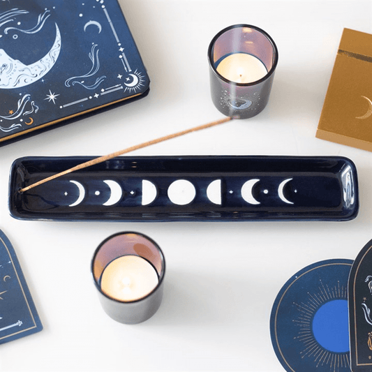Blue Moon Phase Ceramic Incense Ash Catcher With Celestial Design displayed with candles and moon phase items.