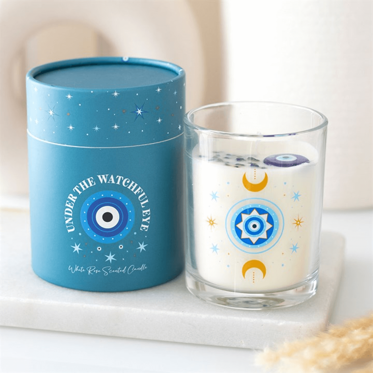 Under Watchful Eyes White Rose Candle With Crystals in glass jar and turquoise box with all-seeing eye design.