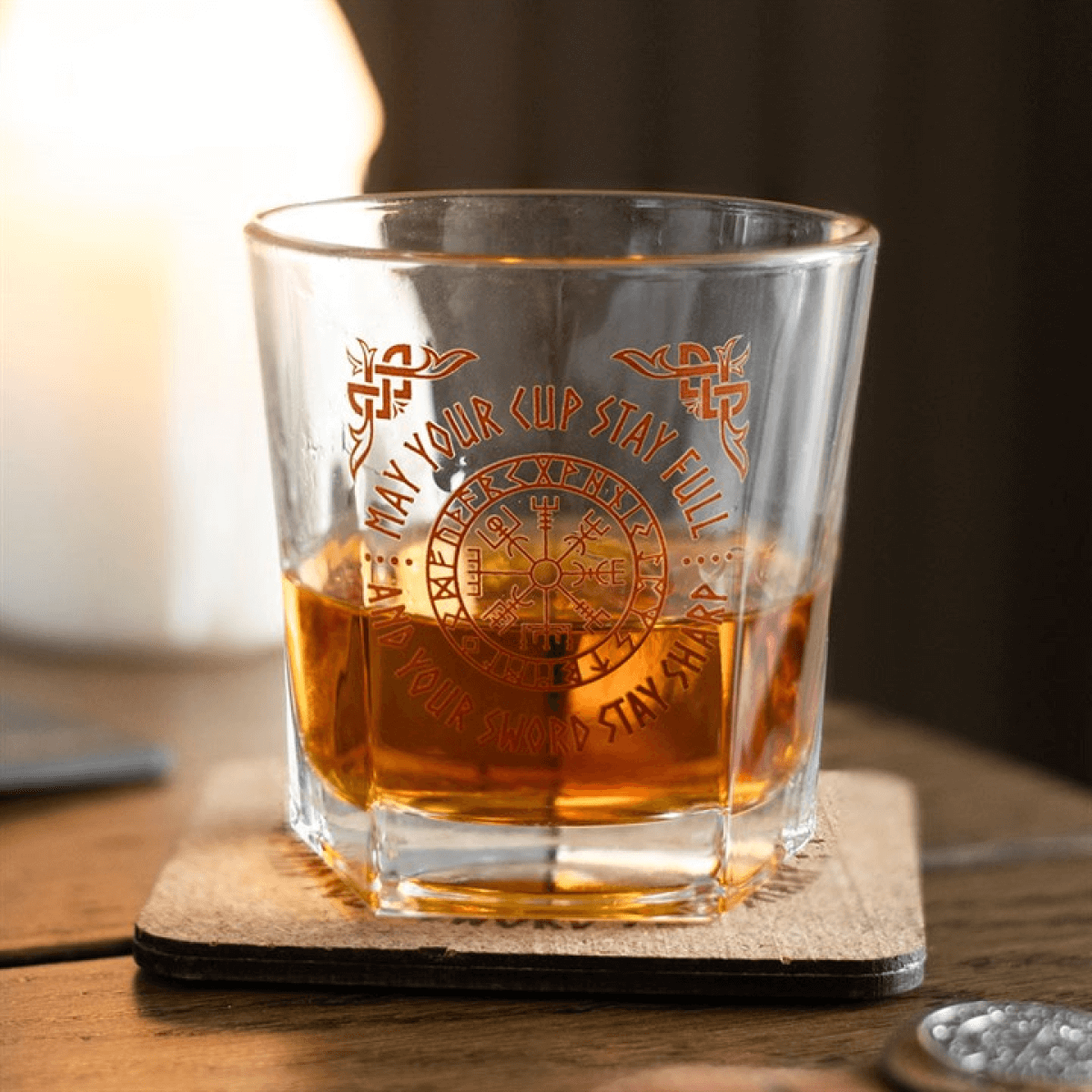 Viking Compass Lowball Glass With Vegvisir Symbol And Matching Cork Coaster filled with whiskey on a wooden table.