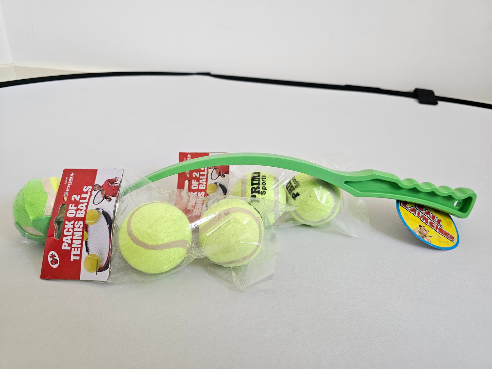 Green tennis ball launcher with two packs of refill tennis balls for dogs at Fetch! Store.