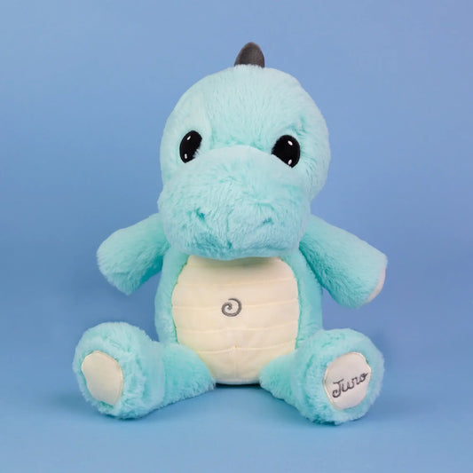 A light blue plush dinosaur toy with a cream-colored belly patch, black eyes, and a small dark horn on its head, sitting against a solid blue background.