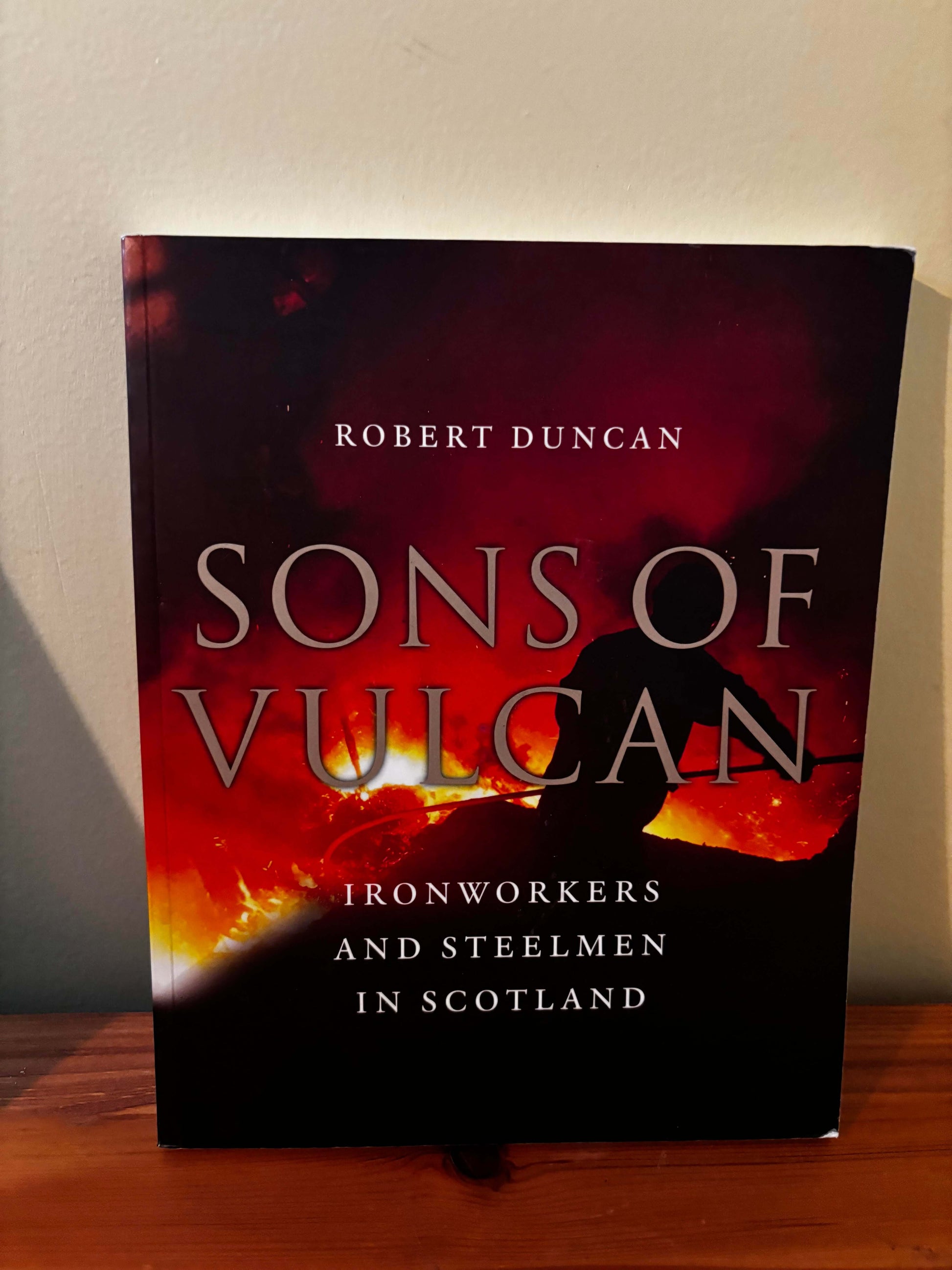 Book titled 'Sons of Vulcan' by Robert Duncan on a wooden surface with a neutral background